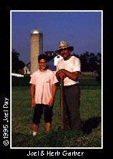 Joel and Herb Garber raking cut alfalfa together for hay bailing.