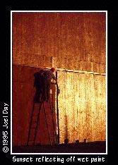 Farmer painting large red barn?subject=with sunset reflecting off of wet paint) near Manheim, Pennsylvania.