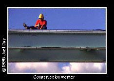 Construction worker fitting pipes on steel girder. 